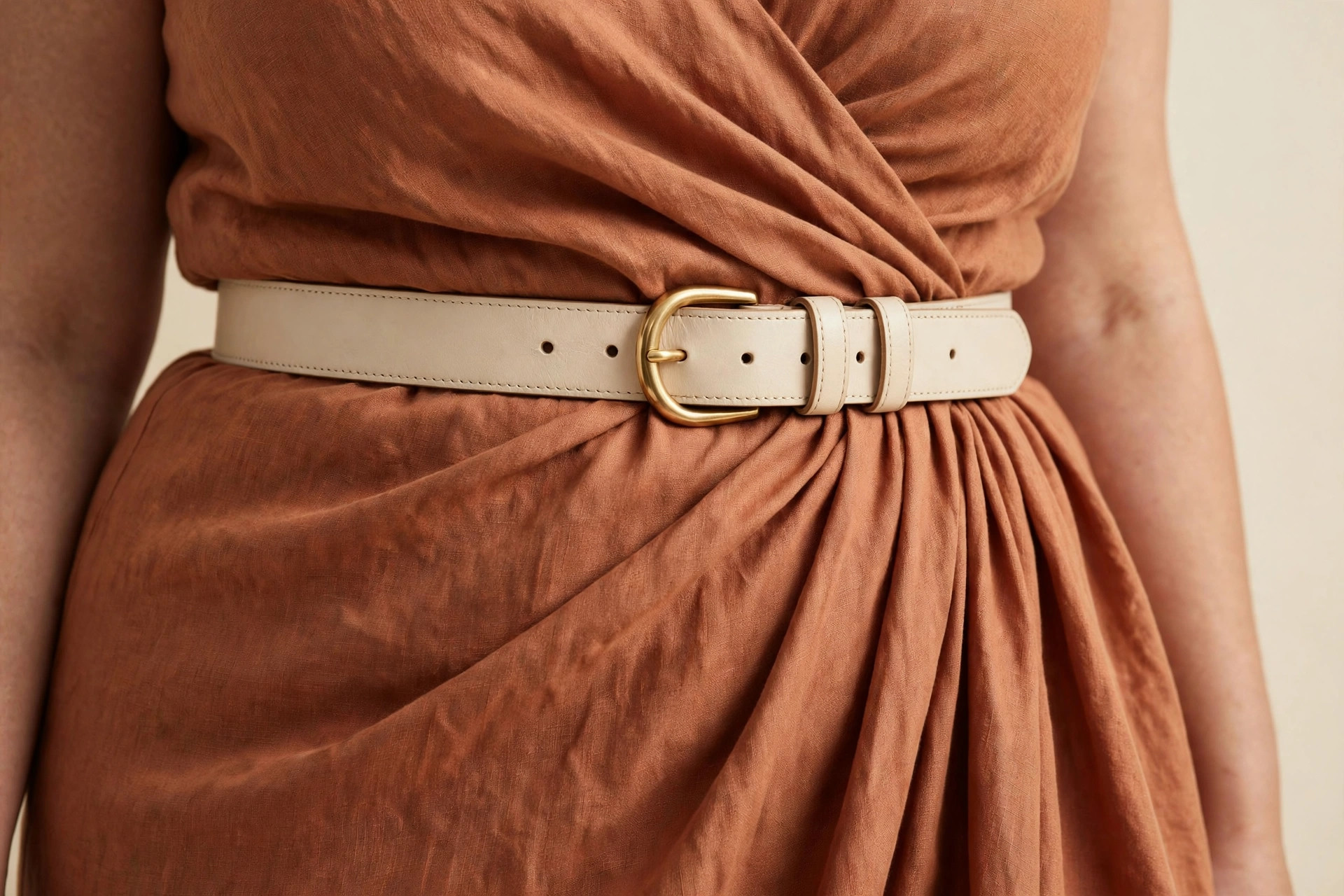 Close-up of a belt cinched at the defined waist of a terracotta wrap dress